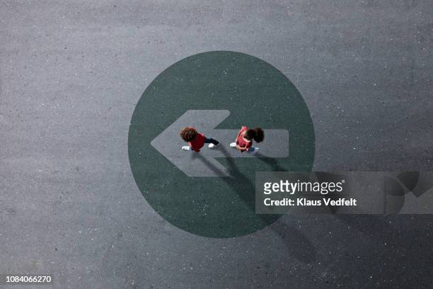 school children dressed in red, walking across painted circle with arrow - 2 runde stock-fotos und bilder