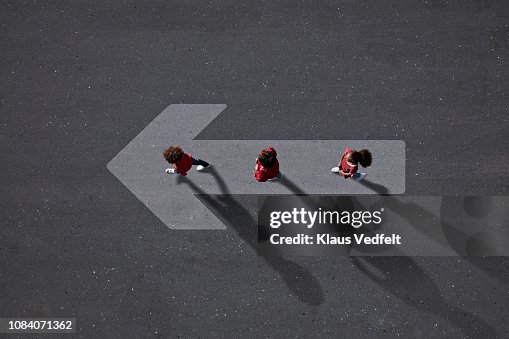 School children dressed in red, walking across big painted arrow School children dressed in red, walking across big painted arrow