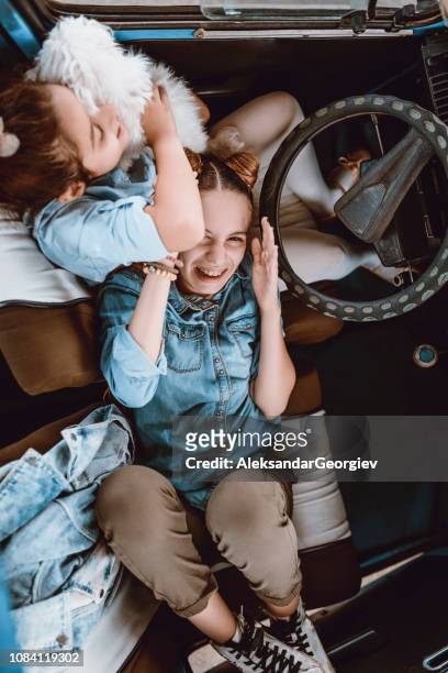 vista de alto ângulo de giro irmãzinhas se divertindo com seu cachorro no carro - family inside car - fotografias e filmes do acervo