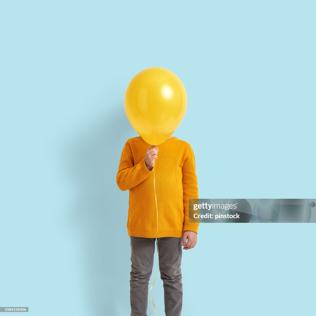 Cute child holding a yellow balloon