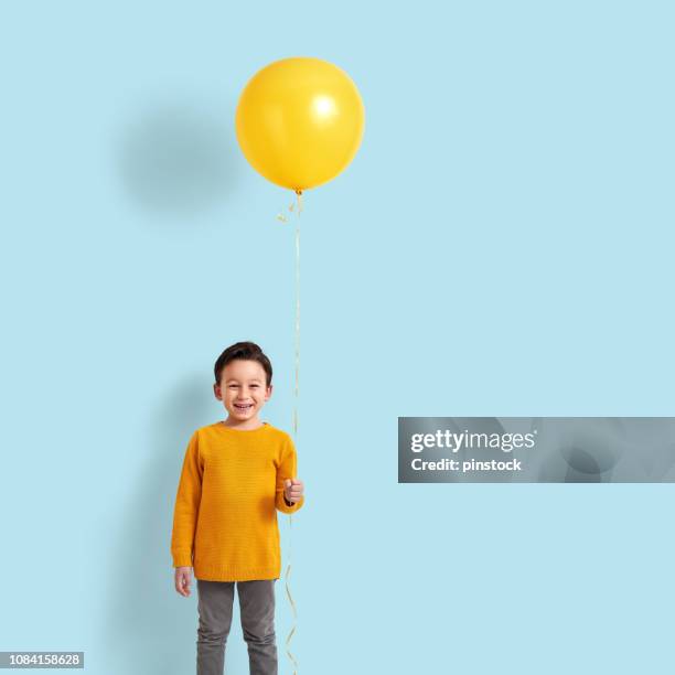 niedlichen kind hält einen gelben ballon - boy holding picture cut out stock-fotos und bilder