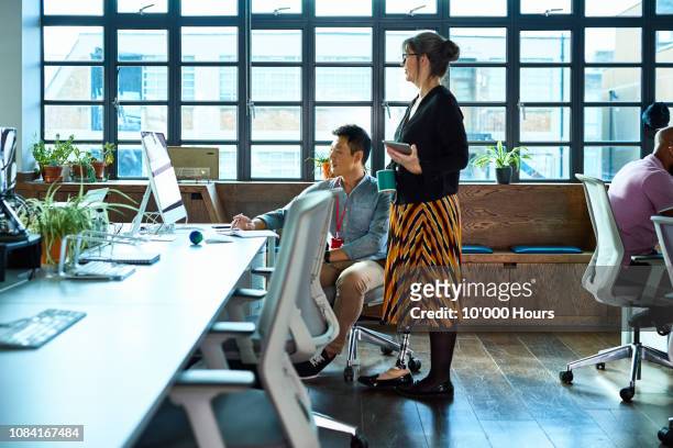 it supporter checking computer with mature woman watching - disabilitycollection stock pictures, royalty-free photos & images