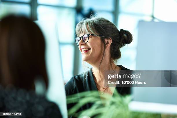 candid portrait of mature businesswoman in glasses laughing - messa a fuoco differenziale foto e immagini stock