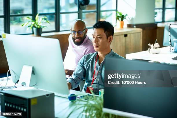 computer programmer working with male colleague in office - help desk stock pictures, royalty-free photos & images