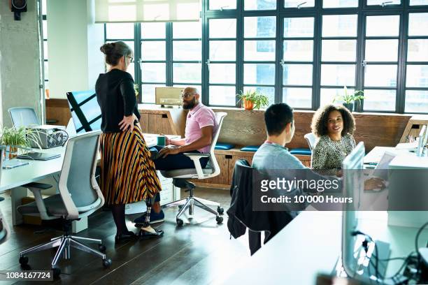 female amputee standing next to male colleague's desk and talking - stress management stockfoto's en -beelden