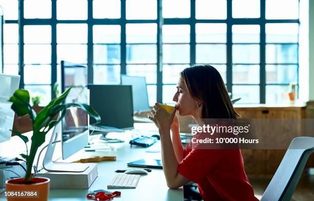 young woman taking coffee break at desk with eyes closed - cup office stock pictures, royalty-free photos & images