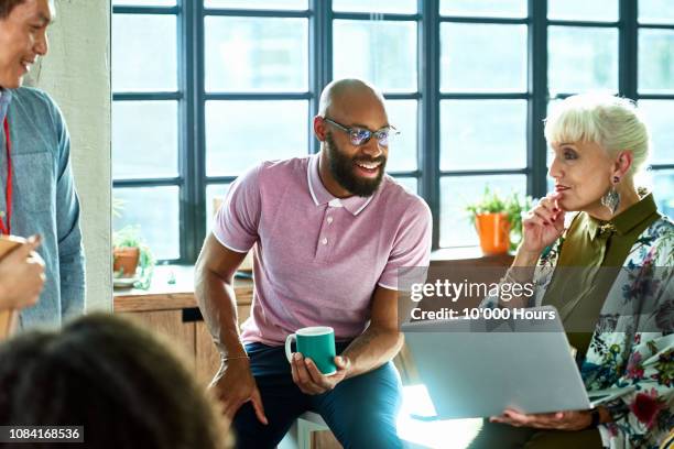 senior woman with laptop listening to male colleague - persuasion business stock pictures, royalty-free photos & images