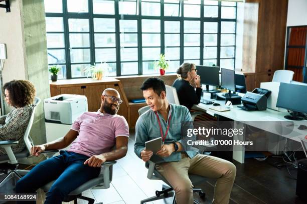 two men chatting in office with digital tablet - scandal imagens e fotografias de stock