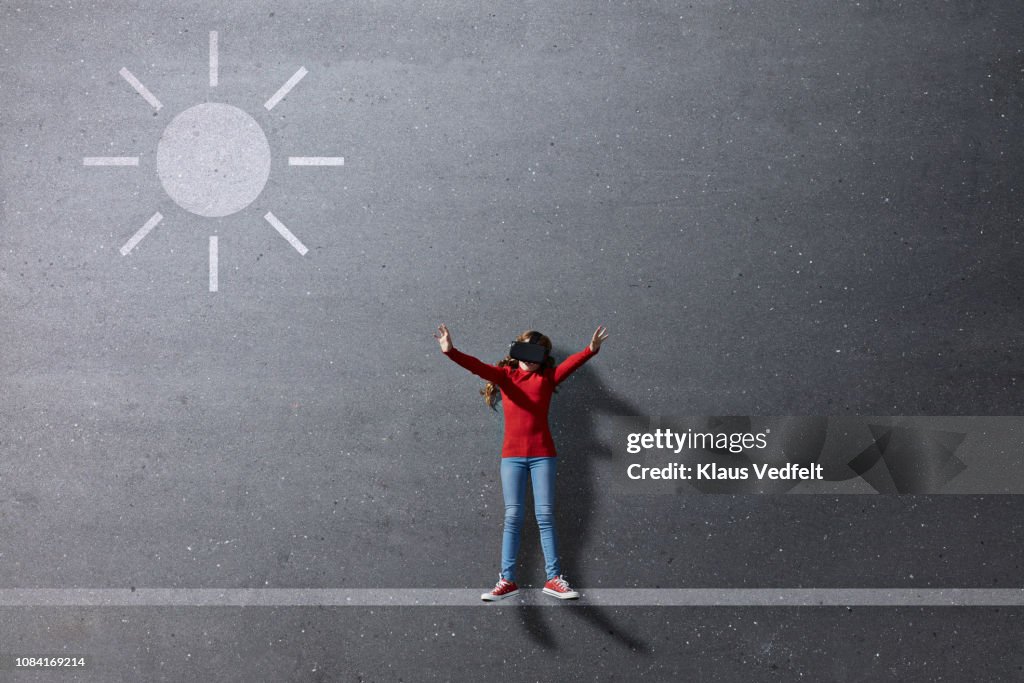 Girl wearing VR goggles standing under imaginary painted sun