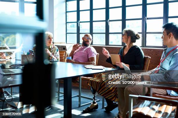 mature woman leading team meeting in board room - disabilitycollection stock pictures, royalty-free photos & images