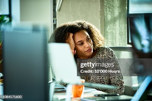 Portrait of mixed race woman looking bored at desk Portrait of mixed race woman looking bored at desk