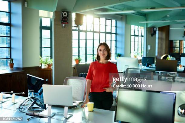 portrait of young female office worker in office smiling towards camera - returning computer stock pictures, royalty-free photos & images