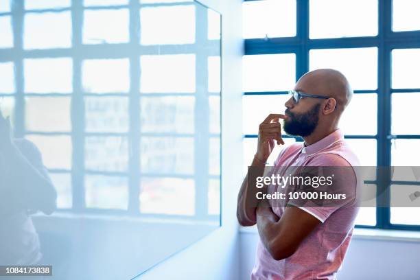 pensive african entrepreneur staring at blank whiteboard in office - thinking outside the box englische redewendung stock-fotos und bilder