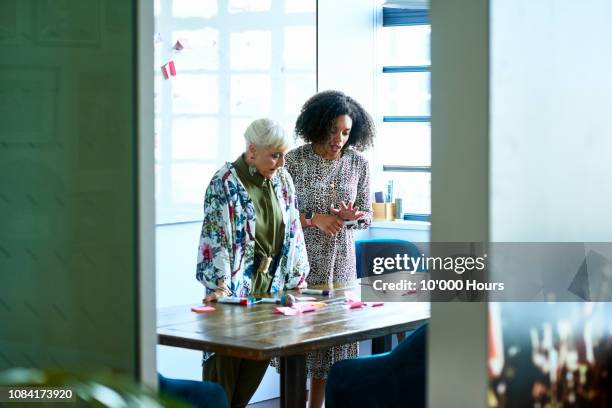 senior female mentor assisting young woman with creative problem solving - thinking outside the box englische redewendung stock-fotos und bilder