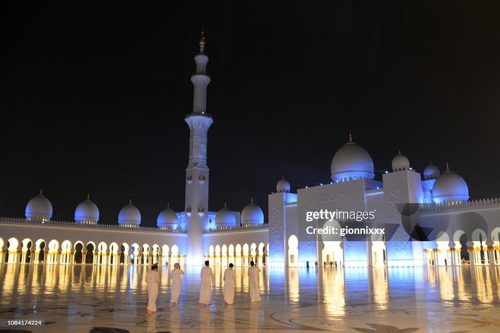 Group of locals in Sheikh Zayed mosque by night, Abu Dhabi, UAE