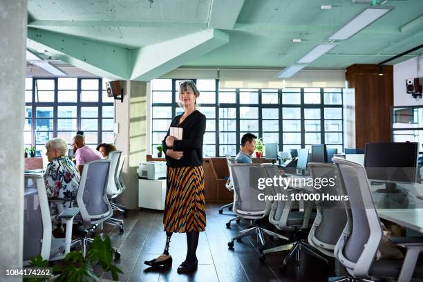 female amputee standing in office looking at camera and smiling - amputee women stockfoto's en -beelden