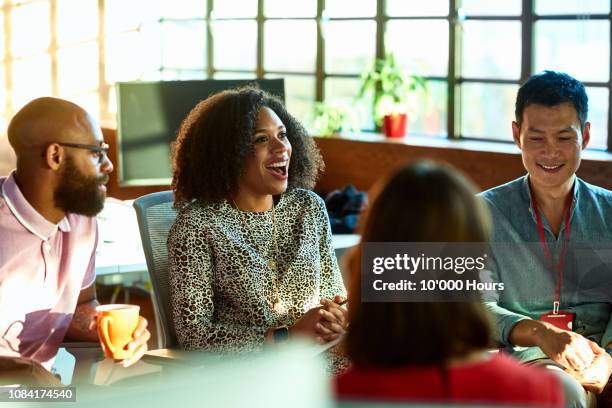 mixed race woman smiling and laughing in relaxed team meeting - modern business people close up stock pictures, royalty-free photos & images
