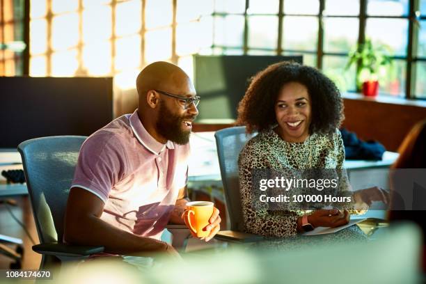 cheerful businessman and woman in office smiling and laughing - working side by side stock pictures, royalty-free photos & images