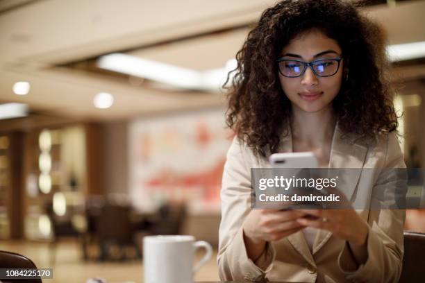businesswoman staying in touch with her clients on business trip - airport waiting lounge imagens e fotografias de stock