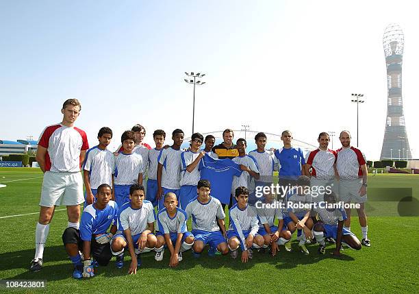 Lucas Neill of the Australian Socceroos poses with a junior football team as he visits the ASPIRE Academy for Sports Excellence on January 27, 2011...