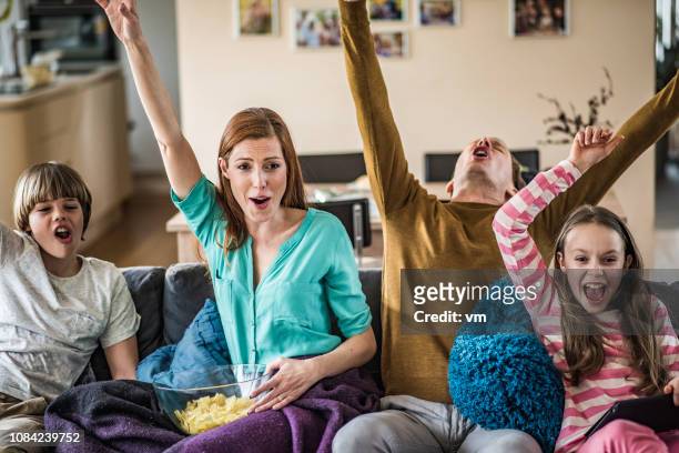 family celebrating on the couch while watching tv - mom cheering stock pictures, royalty-free photos & images