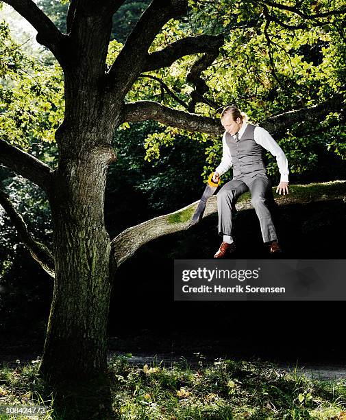 businessman sawing the branch he is occupying - hand saw stock pictures, royalty-free photos & images