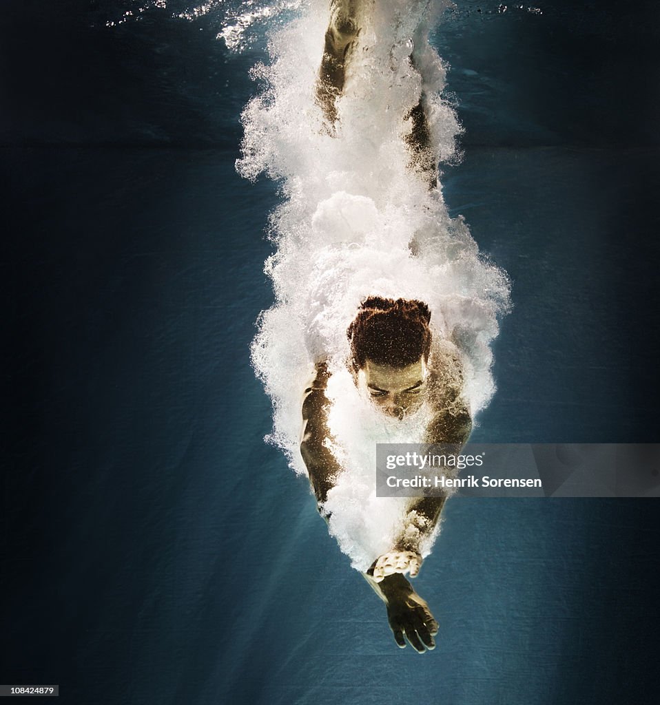 Male swimmer under water with bubbles