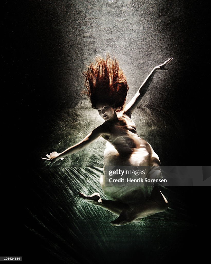 Female in an evening dress sinking under water