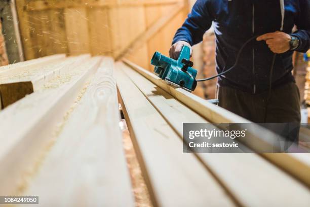 carpenter is planing a wooden plank - man builds his own plane imagens e fotografias de stock