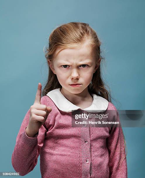 portrait of young girl with raised finger - hand opsteken stockfoto's en -beelden