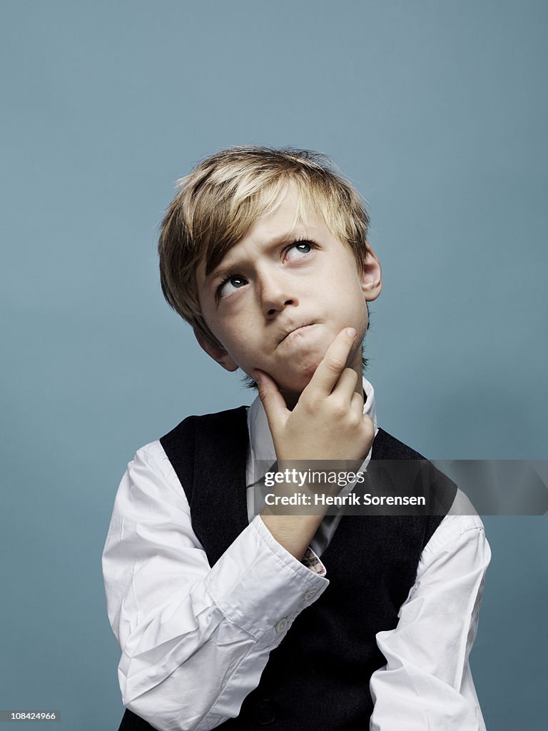 Young boy pondering with hand on chin