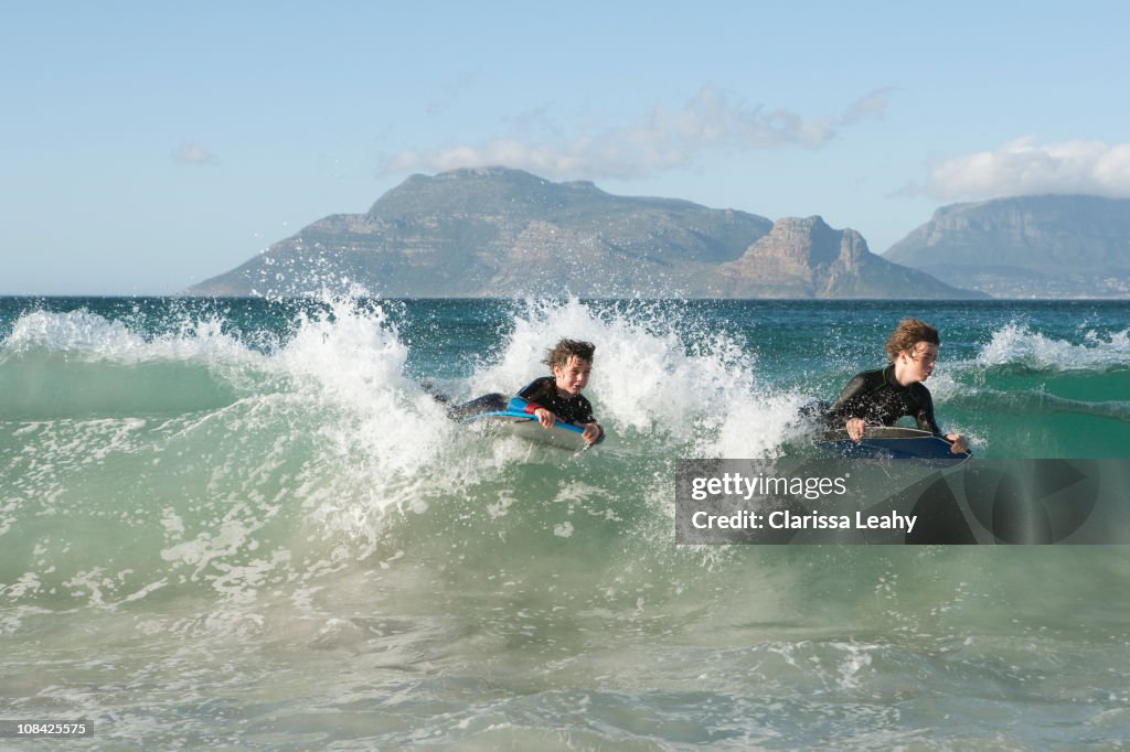 Boys boogie boarding on wave