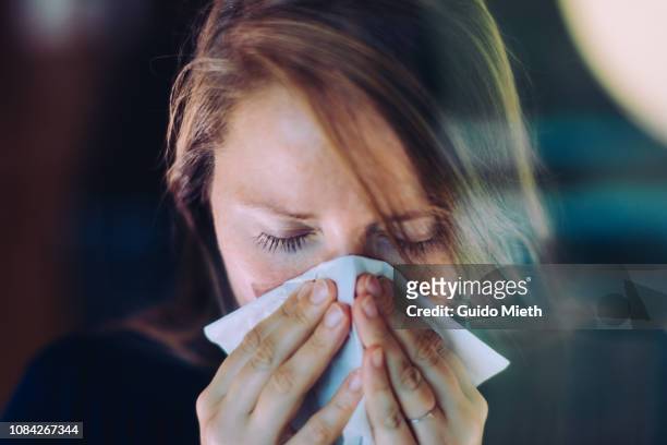 woman sneezing behind a window. - état grippal photos et images de collection
