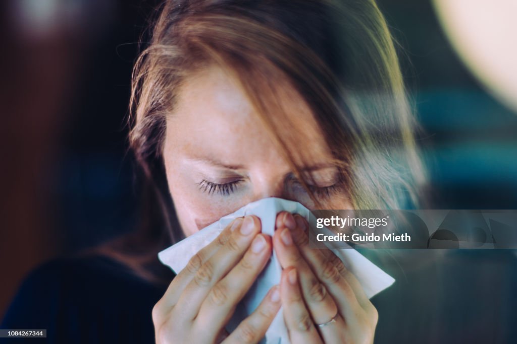 Woman sneezing behind a window.