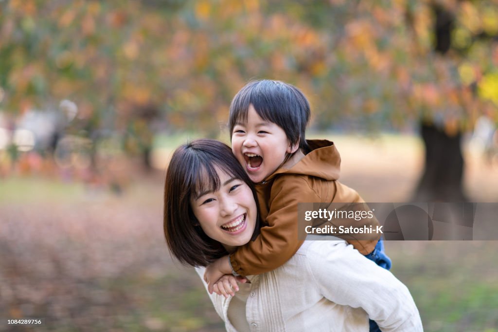 Young mother and son playing together in public park
