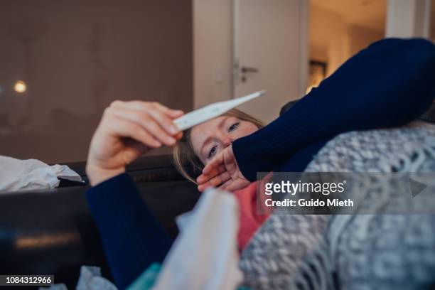 ill woman looking at thermometer. - illness stock pictures, royalty-free photos & images