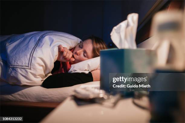 woman coughing in bed. - virus grippal photos et images de collection