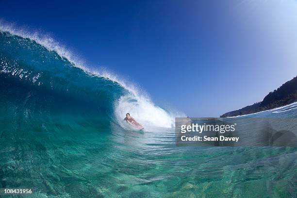a water view of a surfer girl in the tube, in hawaii. - surf tube stock-fotos und bilder