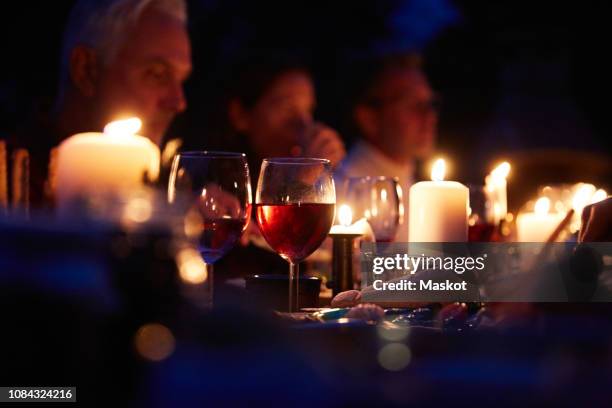 close-up of wineglass and bread by burning candles on dining table at dinner party - burns supper stock pictures, royalty-free photos & images