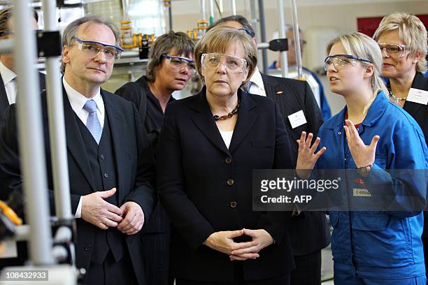 German Chancellor Angela Merkel and Saxony-Anhalt's Economy minister Reiner Haseloff listen to employee Vivian Hernandez-Vega on January 27, 2011 as...