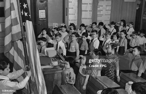 Group of children saluting the American flag at a school in the Chinatown area of Manhattan circa 1960.