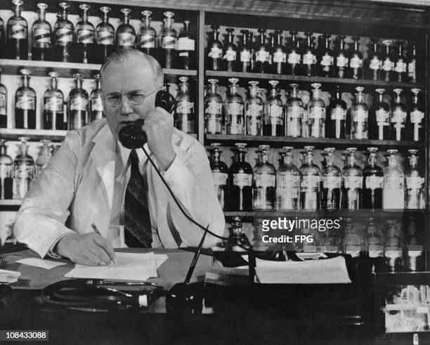 Pharmacist on the telephone inside a drug store circa 1940.
