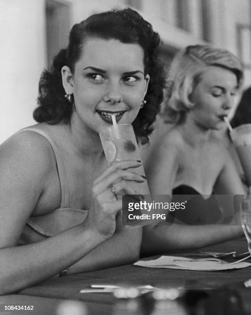 Beauty pageant contestants Elisabeth Valiente and Pat Cooper sip lemonade before the Miss Caribbean Hotel contest held in Miami Beach, Florida in the...