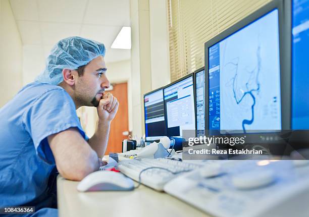 doctor analyses scan of aneurism - operating gown stock pictures, royalty-free photos & images