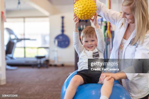 sjukgymnast som arbetar med en ung pojke i kliniken - pediatrician bildbanksfoton och bilder