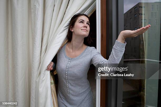 woman checking for rain - wettervorhersage stock-fotos und bilder