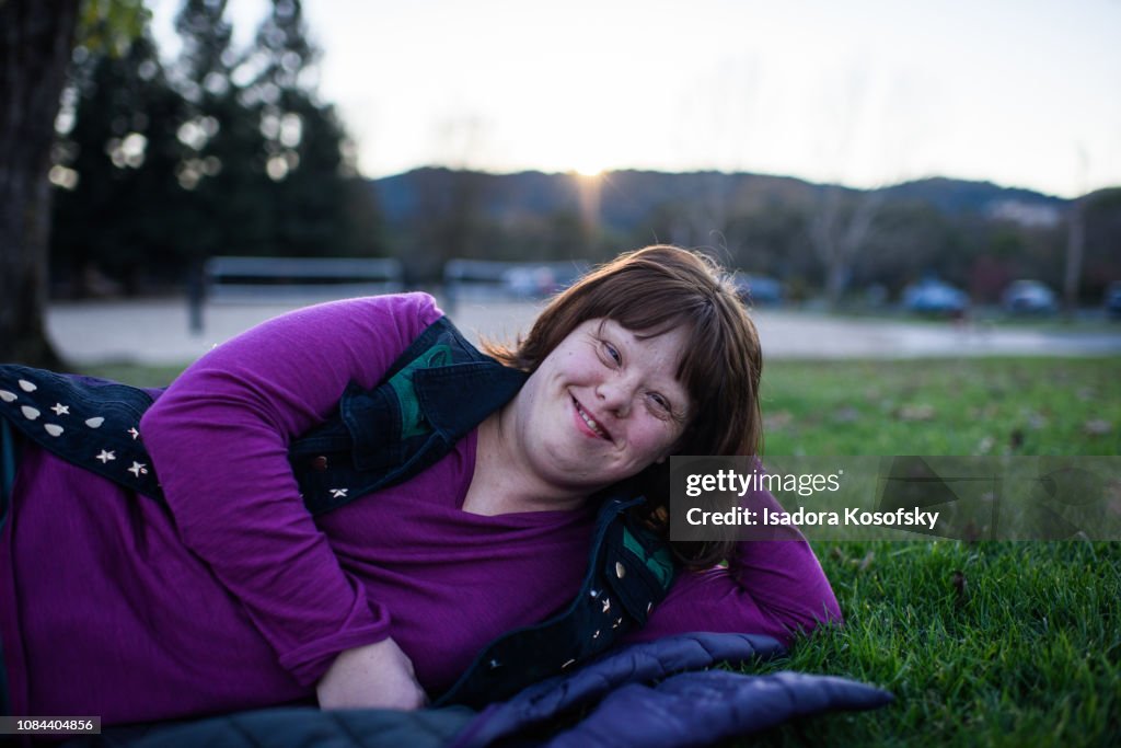 Woman with Down Syndrome relaxes outside.