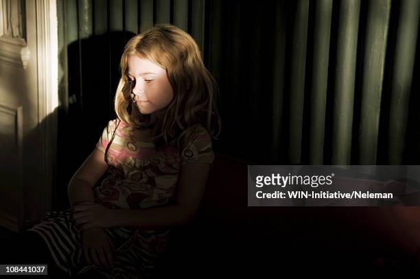 south africa, durban, little girl sitting on sofa - clair obscur stockfoto's en -beelden