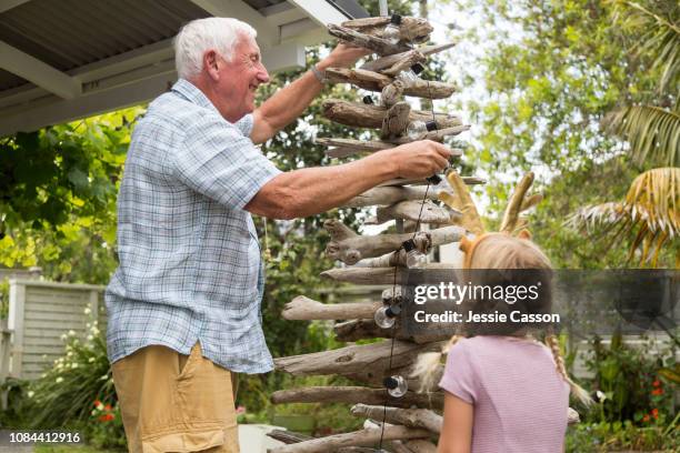 grandfather enjoying decorating christmas tree with granddaughter - new zealand christmas stock pictures, royalty-free photos & images