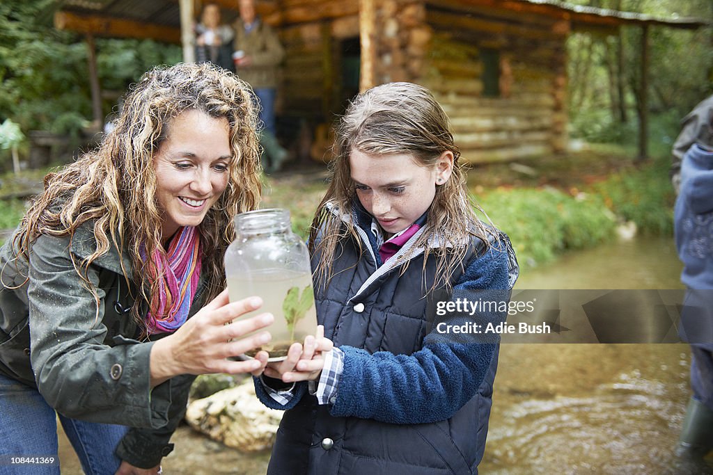 Mom and daughter examining insect in jar